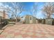The backyard with an outbuilding featuring a unique red and tan tiled patio under a blue sky at 14867 E Harvard Ave, Aurora, CO 80014