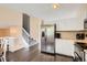 Bright kitchen with stainless steel refrigerator, white cabinets, hardwood floors, and stairway at 11864 N Chase Ct, Westminster, CO 80020
