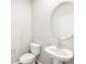 Simple half bathroom with a pedestal sink, round mirror, and toilet in a neutral color scheme at 764 N Tempe St, Aurora, CO 80018