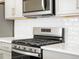 Close up of kitchen appliances, including the range and microwave, with white countertops at 764 N Tempe St, Aurora, CO 80018
