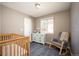 Comfortable Bedroom featuring a rocking chair, wood crib, blue patterned rug and dresser at 200 N Holcomb St, Castle Rock, CO 80104