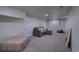 Spacious carpeted basement living room with a comfortable gray sofa and a patterned ottoman at 4267 Federal Blvd, Denver, CO 80211