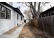 Side yard featuring a new concrete walkway, freshly painted white brick, gravel, and a wooden fence at 4267 Federal Blvd, Denver, CO 80211