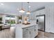 Open kitchen and living area with stainless steel appliances, white cabinetry and large kitchen island at 944 Alpine Ridge St, Erie, CO 80516