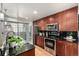 Modern kitchen featuring stainless steel appliances, cherry cabinets, and black subway tile backsplash at 1700 Bassett St # 406, Denver, CO 80202