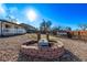 Backyard featuring a unique fire pit and rock landscaping, leading to a bright white home with a lovely deck at 16555 E Wesley Ave, Aurora, CO 80013