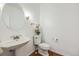 Clean half-bathroom with a pedestal sink, toilet, and a decorative mirror, showcasing a minimalist design at 1274 Meyerwood Ln, Highlands Ranch, CO 80129