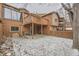 Backyard with a wood fence and patio area is covered in snow; an upper deck is accessible by stairs at 45 Wright Ct, Lakewood, CO 80228