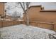 Backyard with a brown fence is covered in snow; a large bare tree stands in the middle at 45 Wright Ct, Lakewood, CO 80228