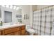 Well-lit bathroom featuring wood cabinets, a sink, a toilet, and a shower with a patterned curtain at 10818 Cimarron St # 1102, Firestone, CO 80504