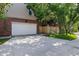A clean, attached garage with extra driveway parking, framed by trees and a wooden fence at 2 S Monroe St, Denver, CO 80209
