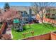 Expansive backyard featuring a large lawn, playset, deck, fire pit, and mature trees at 14533 W 69Th Pl, Arvada, CO 80004