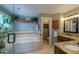 Well-lit bathroom featuring double sinks, granite counters, a soaking tub, and a separate water closet at 14533 W 69Th Pl, Arvada, CO 80004