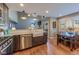Bright kitchen featuring stainless steel appliances, farmhouse sink, dark wood cabinets, and access to dining area at 14533 W 69Th Pl, Arvada, CO 80004
