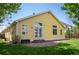Charming yellow home exterior with brick patio, green lawn, white-trimmed windows, and double doors to the backyard at 1606 Iris St, Broomfield, CO 80020