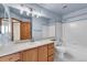 Well-lit bathroom with a wooden vanity, neutral countertop, and white tile tub at 1606 Iris St, Broomfield, CO 80020