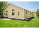 Bright yellow home exterior featuring a well-maintained lawn, windows and access to a brick patio at 1606 Iris St, Broomfield, CO 80020