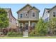 Charming two-story home featuring gray siding, brick accents, landscaped yard, and welcoming front porch at 10479 E 25Th Dr, Aurora, CO 80010