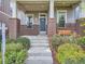 Inviting front porch with brick pillars, a cozy porch swing, and meticulously manicured landscaping at 10479 E 25Th Dr, Aurora, CO 80010