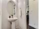 Stylish powder room showcasing a pedestal sink, modern fixtures, and doorway to the kitchen at 10479 E 25Th Dr, Aurora, CO 80010