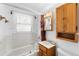 Bathroom with white tile, wood cabinets, a shower/tub combination, and classic fixtures at 75 Vrain St, Denver, CO 80219