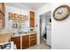 The kitchen features wood cabinets, a stainless steel sink, a rooster themed window covering and a view to the laundry at 75 Vrain St, Denver, CO 80219