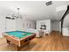 Billiard table illuminated by a modern chandelier in a spacious game room with hardwood floors at 2025 Fenton St, Edgewater, CO 80214