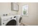 Functional laundry room with modern washer and dryer, cabinet, and window for natural light at 3831 E 141St Ave, Thornton, CO 80602