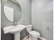 Cozy powder room featuring a pedestal sink, round mirror, and light gray walls at 3831 E 141St Ave, Thornton, CO 80602