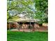 Charming backyard with a brick house, lush green lawn, covered patio, and mature trees, perfect for outdoor living at 1669 S Kearney St, Denver, CO 80224