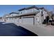 View of the exterior elevation with brick and gray siding, including three garages with a parking space in front at 6722 S Winnipeg Cir # 102, Aurora, CO 80016