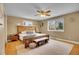 Bedroom boasts a natural wood bed frame, hardwood floors, bright windows, and modern ceiling fan at 12821 W 60Th Ave, Arvada, CO 80004