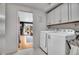 Laundry room boasts white washer and dryer, white cabinets, and view of the backyard from the door at 12821 W 60Th Ave, Arvada, CO 80004