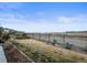 Well-maintained backyard with lush green grass, mature landscaping, a black fence, and picturesque views of the lake at 26741 E Peakview Pl, Aurora, CO 80016