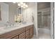 Modern bathroom featuring double vanity, marble countertops and floors, and a glass enclosed shower at 26741 E Peakview Pl, Aurora, CO 80016