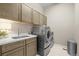 Well-equipped laundry room with front load washer and dryer, sink, and ample cabinet space at 26741 E Peakview Pl, Aurora, CO 80016