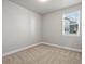 This bedroom has neutral-colored carpet, trim, and paint and a window overlooking the neighborhood at 12242 W 56Th Pl, Arvada, CO 80002