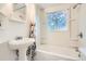All-white bathroom with tub, shower, sink, and window at 7957 Elm St, Louviers, CO 80131
