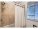Tiled bathtub and shower combo with window bringing in light at 7957 Elm St, Louviers, CO 80131