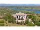 Stunning home with fountain and circular driveway, surrounded by mature trees and a lake backdrop at 7615 Lemon Gulch Way, Castle Rock, CO 80108