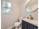 Stylish powder room with a navy vanity, modern fixtures, and a round mirror at 13244 Kearney St, Thornton, CO 80602
