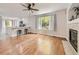 Bright living room with hardwood floors, fireplace, ceiling fan, and view into the modern kitchen area at 13244 Kearney St, Thornton, CO 80602