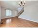 Open-concept living room with hardwood floors, staircase, white door, and ample natural light at 13244 Kearney St, Thornton, CO 80602