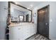 Bathroom featuring double vanity sinks, a large framed mirror, and a wood-look tile floor at 5753 S Kittredge St, Centennial, CO 80015