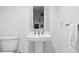 Small bathroom with a pedestal sink, toilet and decorative mirror on the neutral painted wall, towel to the side at 6219 S Krameria St, Centennial, CO 80111