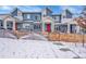 Charming blue townhomes with red doors and white trim, surrounded by a rustic wooden fence in winter at 6211 W 28Th Ct, Wheat Ridge, CO 80214