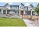 Well-maintained townhouse complex with blue siding, white trim, red doors, and shared grassy lawn and walkway at 6211 W 28Th Ct, Wheat Ridge, CO 80214