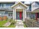 Charming townhouse entrance featuring a covered porch, red door, blue siding, and well-kept landscaping at 6211 W 28Th Ct, Wheat Ridge, CO 80214