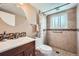 Updated bathroom featuring a walk-in shower with tile surround and a modern vanity with a round mirror at 13086 E Alaska Ave, Aurora, CO 80012