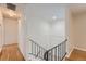 Well-lit hallway and staircase showcasing hardwood floors, white walls, and black iron railing details at 13086 E Alaska Ave, Aurora, CO 80012